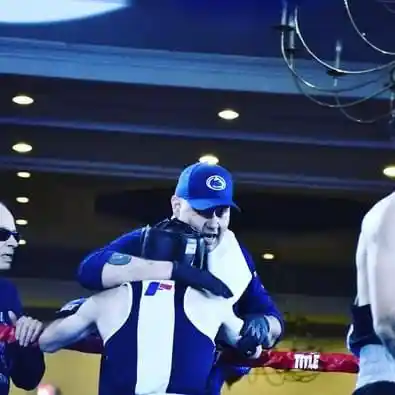 Coach Derek Roth on the ropes with a Penn State boxer at the competition ring