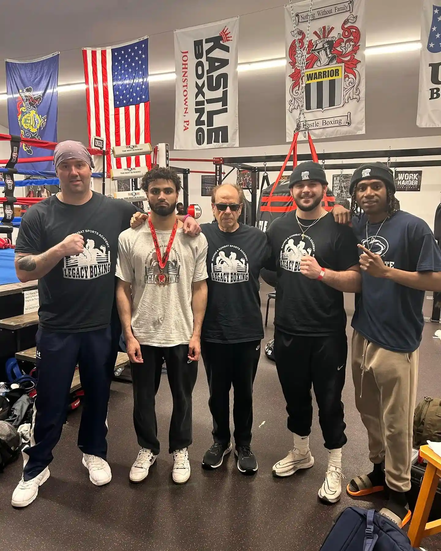 Coach Roth with team boxers in Legacy shirts, one holding a competition medal