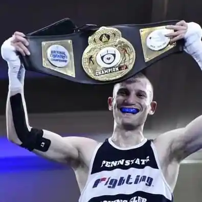 Penn State boxer showing off his championship belt from personalized coaching with Derek Roth