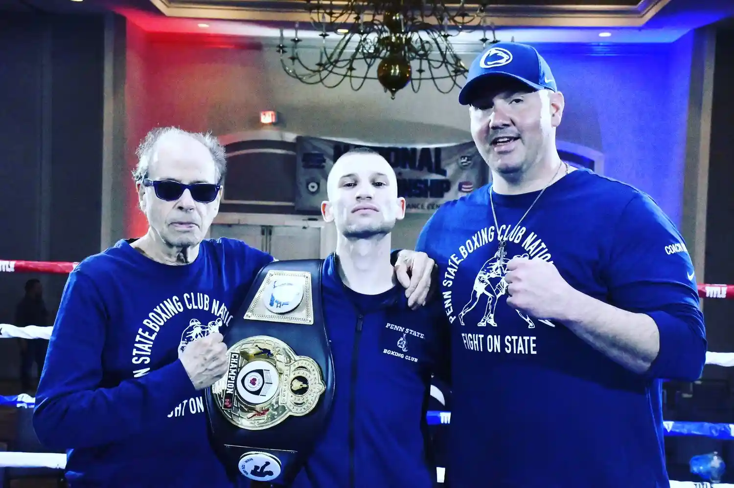 Penn State boxer winning photoshoot with belt and Coach Derek Roth